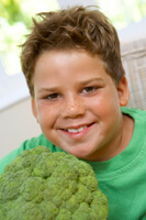 smiling boy holding head of broccoli